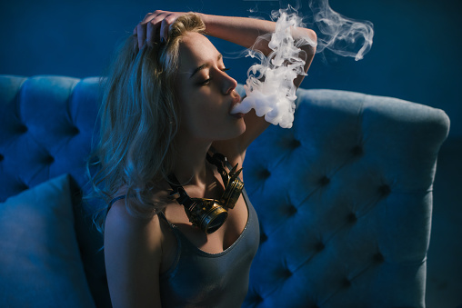 Young beautiful woman smoking ( vaping ) e cigarette with smoke